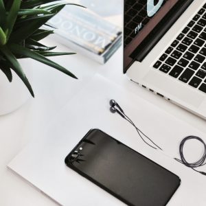 Minimalist workspace with a laptop, smartphone, earphones, and a green plant.