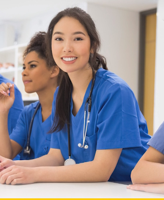 Smiling female medical professionals in blue scrubs with stethoscopes.